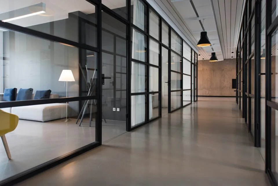 A corridor of glass-walled offices with a polished concrete floor.
