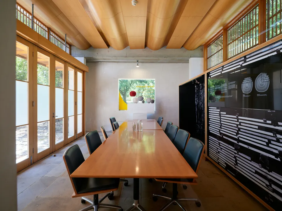 A long wooden conference table with the chairs tucked in and the screen off.