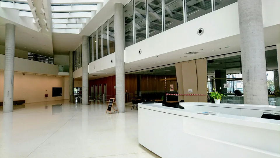 A bright white building lobby with a reception desk and a polished floor.